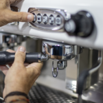 Detalle del grupo de una máquina de café. El barista está colocando el portafiltros.